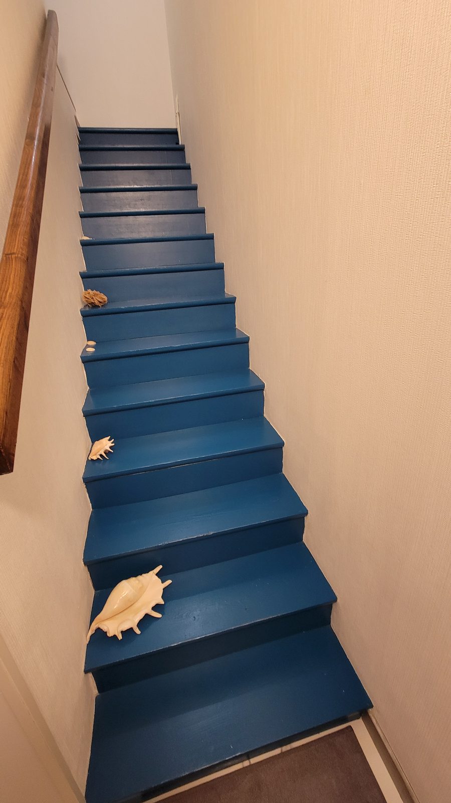 Escalier bleu menant à l’étage, décoré de coquillages