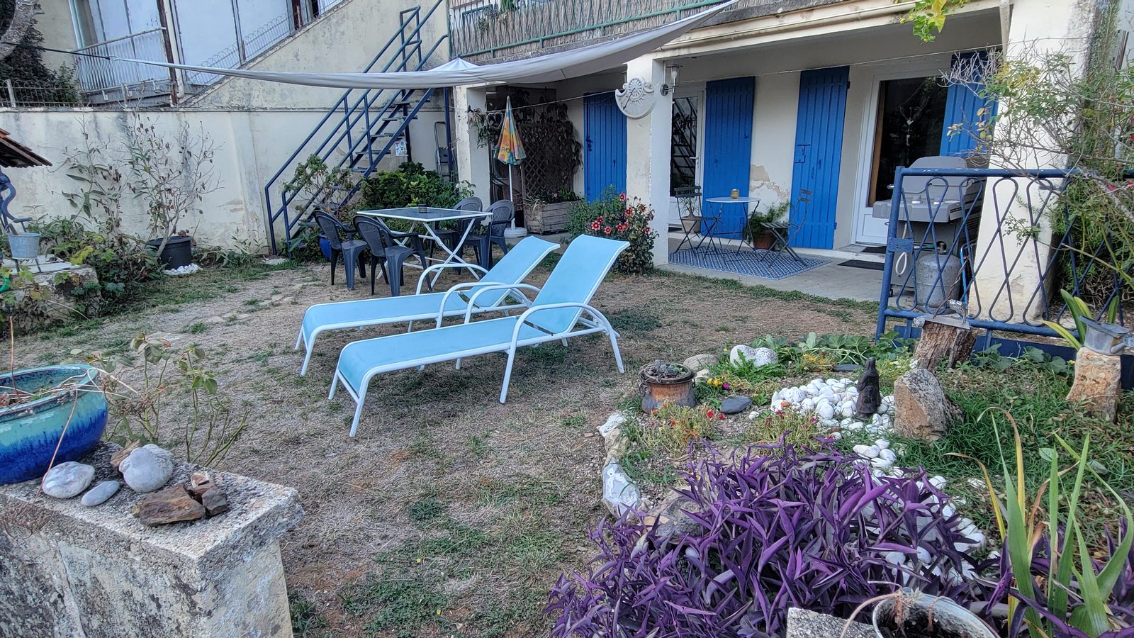 Le jardin de l’appartement avec ses transats, sa rocaille et ses plantes fleuries