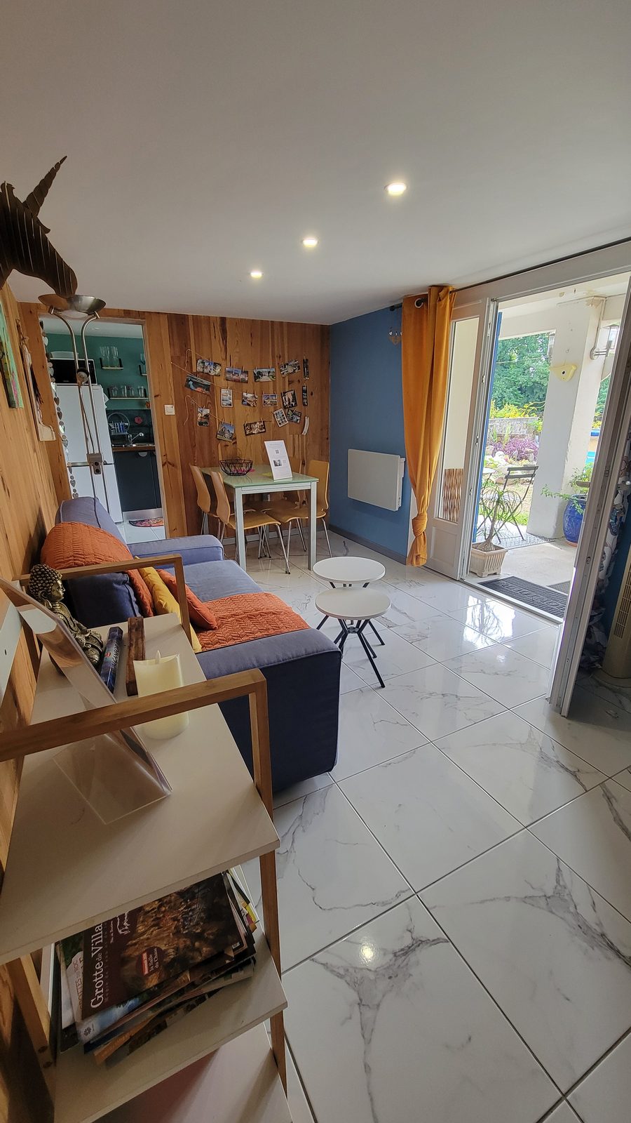 Pièce de vie de l’appartement : canapé, coin repas et porte-fenêtre ouverte sur le jardin